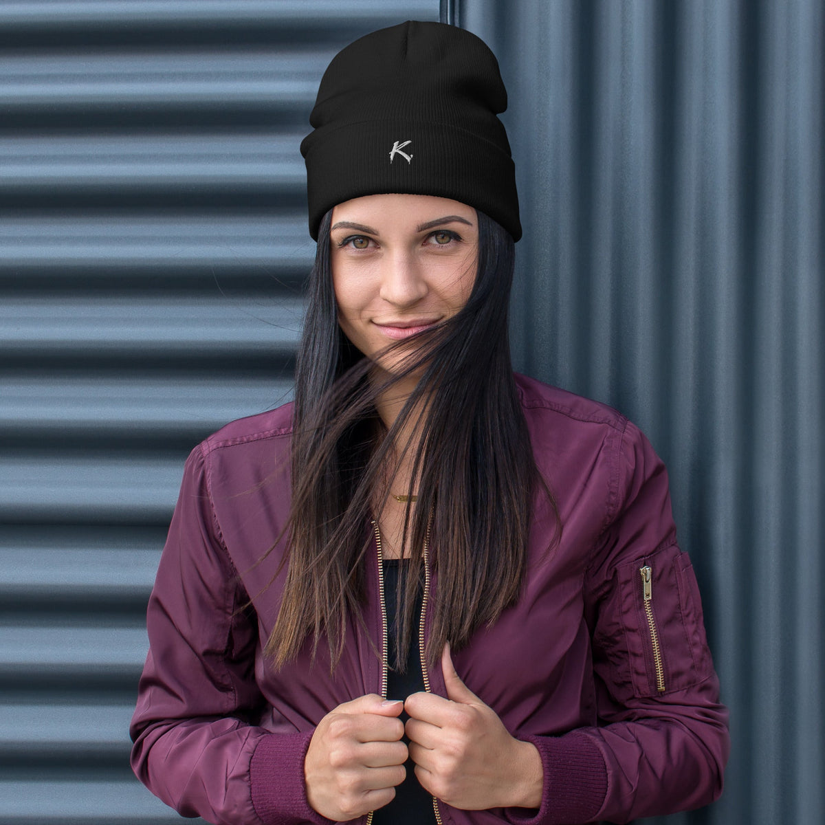 Woman wearing a black Urban Fashion & Streetwear | Craftklart embroidered beanie against a dark corrugated wall