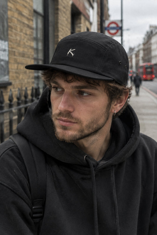 A man wearing a black Urban Fashion & Streetwear | Craftklart five-panel cotton camper cap with a low profile.