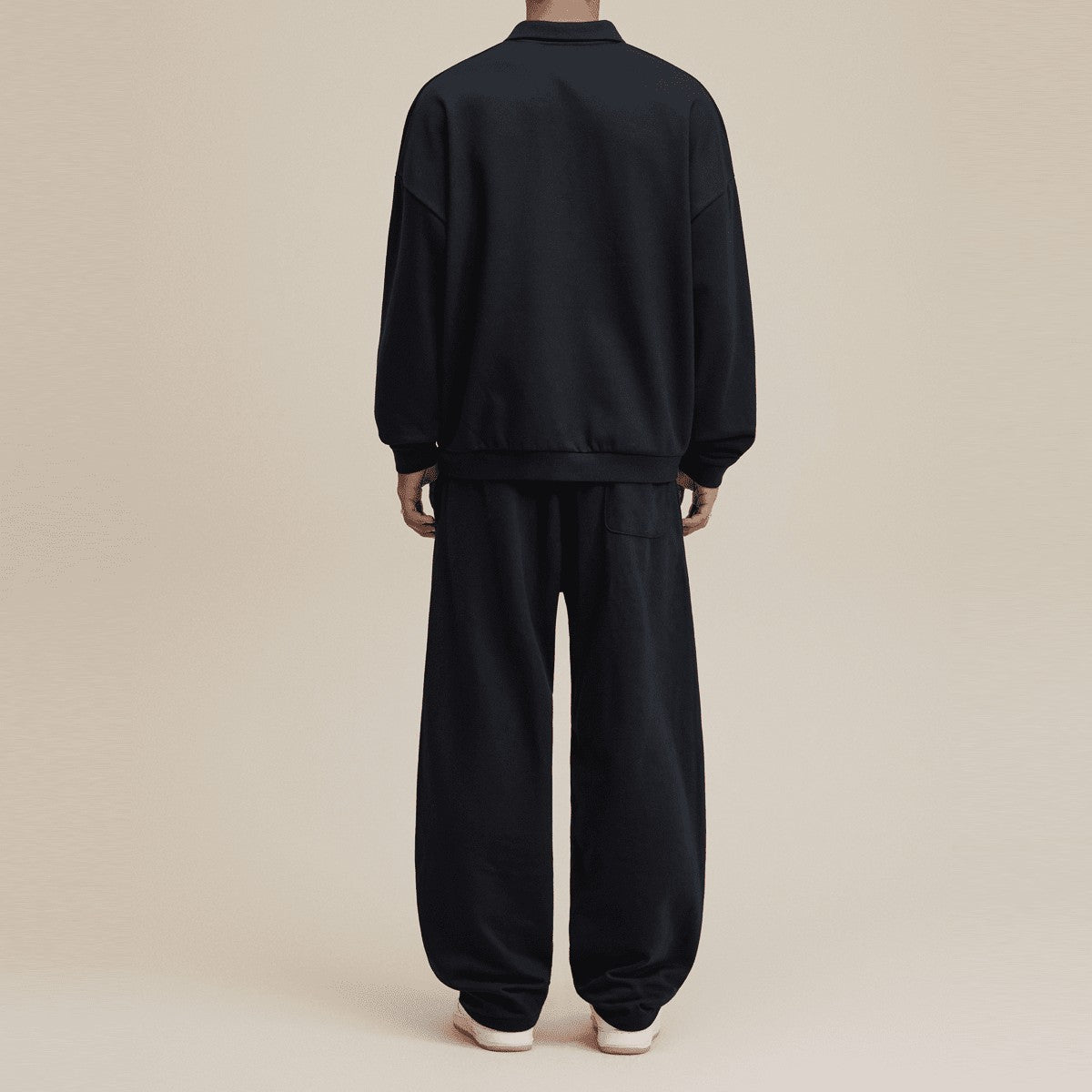 Back view of a man wearing a black Urban Fashion & Streetwear | Craftklart half-placket polo sweatshirt and matching pants.
