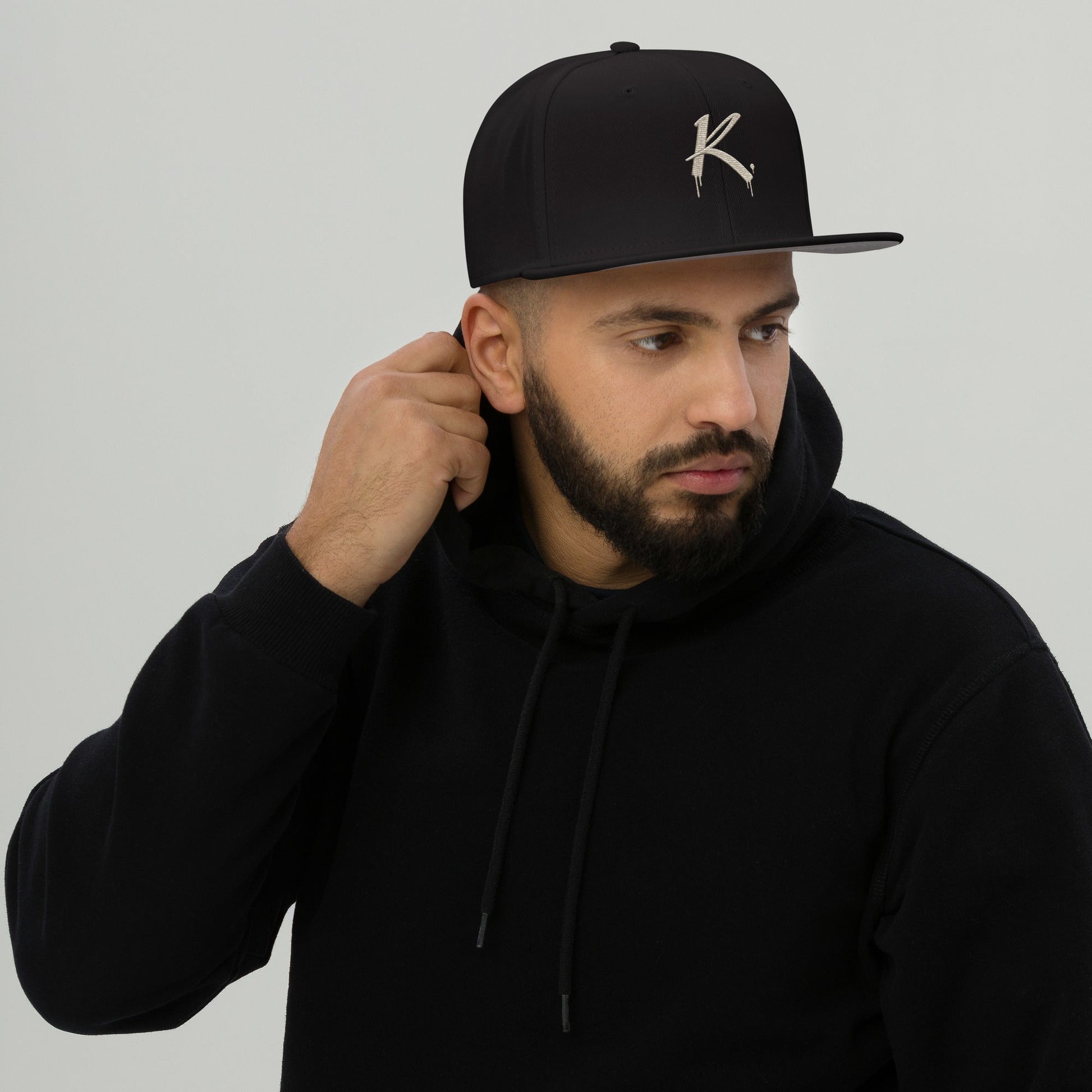 Urban Fashion & Streetwear | Craftklart black snapback cap with flat visor worn by a man in a black hoodie