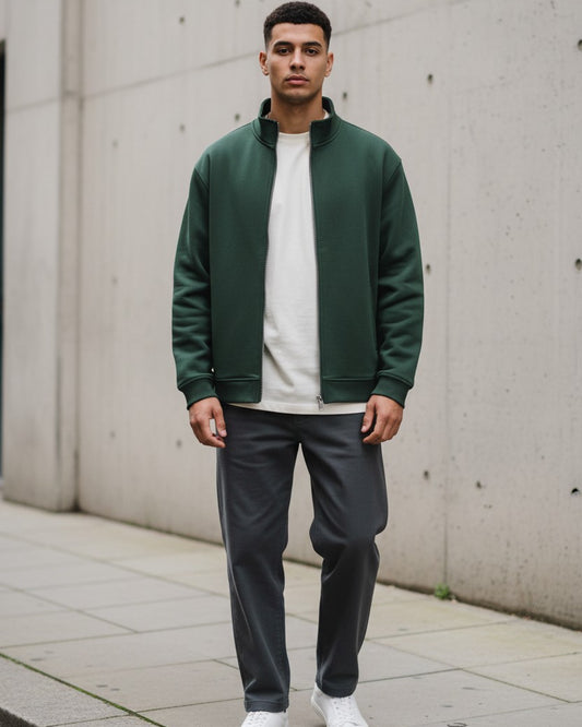 Model wearing a blackish green Craftklart stand collar jacket over a white tee and dark trousers on a city street.