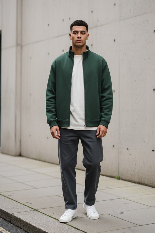 Model wearing a blackish green Craftklart stand collar jacket over a white tee and dark trousers on a city street.