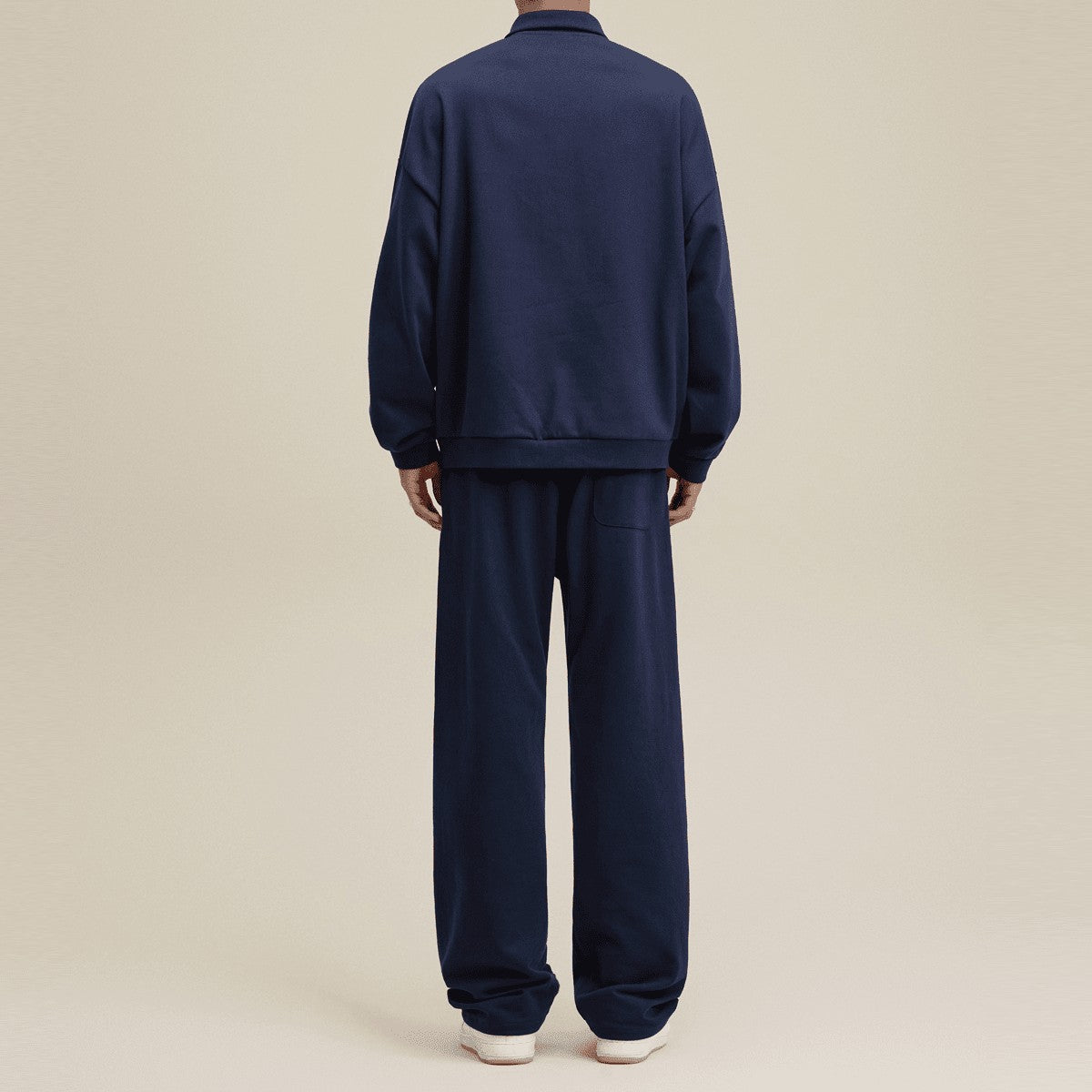 Back view of a man wearing a navy blue Urban Fashion & Streetwear | Craftklart half-placket polo sweatshirt and pants.
